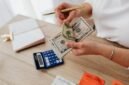 Seorang pemilik usaha kecil sedang serius menghitung laporan keuangan, menunjukkan pentingnya pencatatan detail untuk memahami kondisi finansial bisnis. Pengelolaan keuangan yang cermat adalah kunci keberlanjutan setiap UMKM.