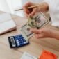 Seorang pemilik usaha kecil sedang serius menghitung laporan keuangan, menunjukkan pentingnya pencatatan detail untuk memahami kondisi finansial bisnis. Pengelolaan keuangan yang cermat adalah kunci keberlanjutan setiap UMKM.