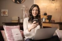 Seorang pelaku usaha mikro, kecil, dan menengah (UMKM) sedang berinteraksi dengan laptopnya di meja kerja rumah, menggambarkan bagaimana teknologi digital menjadi tulang punggung pemasaran produk-produknya. Gambar ini merefleksikan semangat kewirausahaan modern yang memanfaatkan platform daring untuk menjangkau pelanggan lebih luas.