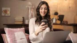 Seorang pelaku usaha mikro, kecil, dan menengah (UMKM) sedang berinteraksi dengan laptopnya di meja kerja rumah, menggambarkan bagaimana teknologi digital menjadi tulang punggung pemasaran produk-produknya. Gambar ini merefleksikan semangat kewirausahaan modern yang memanfaatkan platform daring untuk menjangkau pelanggan lebih luas.