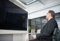 Gambar menunjukkan seorang profesional yang sedang menganalisis data di depan layar komputer yang menampilkan berbagai grafik, melambangkan kompleksitas dan pentingnya strategi bisnis digital berbasis data. Ini menggambarkan bagaimana perusahaan modern memanfaatkan teknologi untuk memahami tren pasar dan perilaku konsumen.