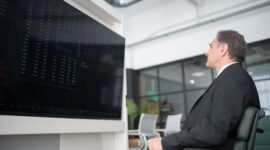 Gambar menunjukkan seorang profesional yang sedang menganalisis data di depan layar komputer yang menampilkan berbagai grafik, melambangkan kompleksitas dan pentingnya strategi bisnis digital berbasis data. Ini menggambarkan bagaimana perusahaan modern memanfaatkan teknologi untuk memahami tren pasar dan perilaku konsumen.