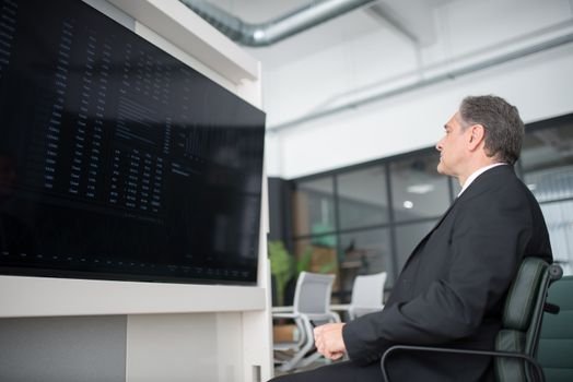 Gambar menunjukkan seorang profesional yang sedang menganalisis data di depan layar komputer yang menampilkan berbagai grafik, melambangkan kompleksitas dan pentingnya strategi bisnis digital berbasis data. Ini menggambarkan bagaimana perusahaan modern memanfaatkan teknologi untuk memahami tren pasar dan perilaku konsumen.