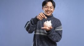 Seorang wirausahawan muda sedang serius menghitung dan merencanakan alokasi dana, menunjukkan pentingnya manajemen keuangan yang cermat sebagai modal awal membangun sebuah usaha. Meja di depannya dipenuhi catatan dan perangkat yang mendukung perencanaan strategis untuk mencapai tujuan bisnis.