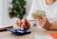 Seorang pemilik UMKM dengan serius menghitung laporan keuangan, menunjukkan komitmen terhadap pengelolaan finansial yang cermat demi keberlanjutan usahanya. Setiap angka yang dicatat adalah cerminan dari potensi pertumbuhan bisnis di masa depan.