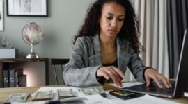 Seorang pemilik UMKM tengah fokus menghitung laporan keuangan dengan cermat, menggambarkan pentingnya pengelolaan finansial yang teliti untuk menjaga keberlangsungan usaha. Gambar ini menyoroti dedikasi para pelaku UMKM dalam memastikan setiap rupiah usaha tercatat dengan baik demi masa depan bisnis yang lebih stabil.