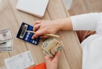 Seorang pemilik usaha mikro tengah fokus menghitung pendapatan dan pengeluaran harian, merefleksikan pentingnya pencatatan keuangan yang teliti untuk menjaga kesehatan bisnis. Disiplin dalam mengelola setiap rupiah menjadi kunci utama agar UMKM dapat terus beroperasi dan berkembang di tengah persaingan pasar yang ketat.
