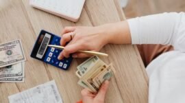 Seorang pemilik usaha mikro tengah fokus menghitung pendapatan dan pengeluaran harian, merefleksikan pentingnya pencatatan keuangan yang teliti untuk menjaga kesehatan bisnis. Disiplin dalam mengelola setiap rupiah menjadi kunci utama agar UMKM dapat terus beroperasi dan berkembang di tengah persaingan pasar yang ketat.