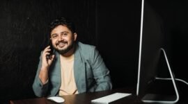 Seorang wirausahawan muda tersenyum di depan laptopnya, merefleksikan semangat dan kreativitas yang dibutuhkan untuk membangun bisnis dari nol dengan memanfaatkan teknologi. Gambar ini menunjukkan bahwa kesuksesan bukan hanya milik mereka yang bermodal besar, melainkan juga mereka yang gigih dan cerdas dalam memanfaatkan peluang.
